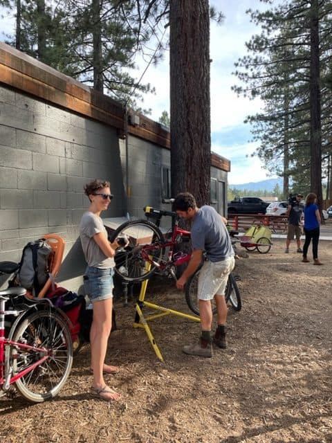 Two volunteers fixing a bike on a repair stand outside a community building